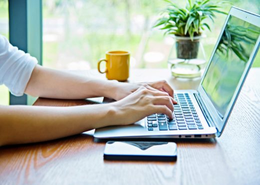 Woman hand typing on laptop in restaurant